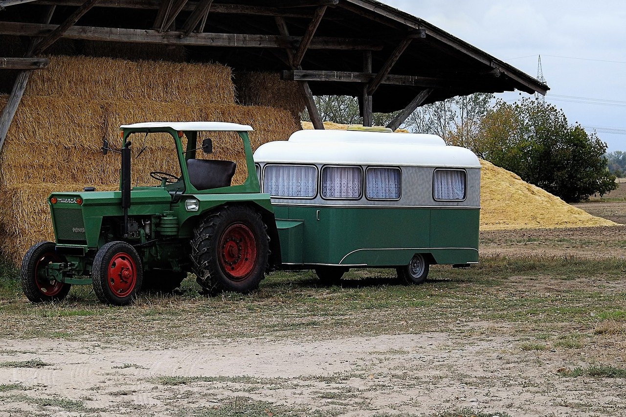 Das Bild zeigt einen Traktor mit angehängtem Wohnwagen.